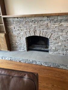 Custom stone fireplace with large mantle, dark wood built-ins, and handcrafted shelving in Doylestown, Pennsylvania.